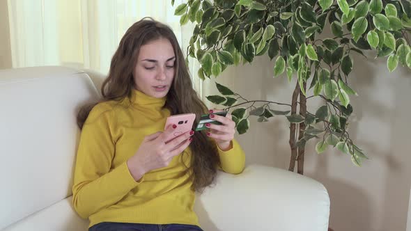 Young Teenage Girl Making Online Payment With Smart Phone and Credit Card at Home