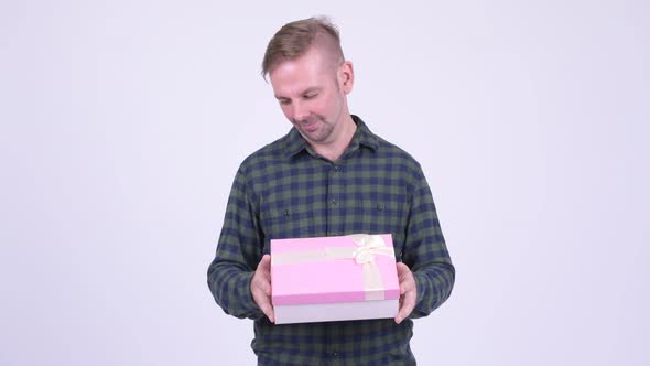 Happy Blonde Hipster Man Thinking While Holding Gift Box