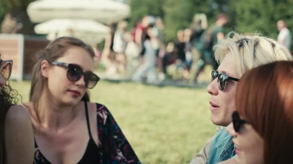 Group of friends sitting together on the grass at music festival. Shot with RED helium camera in 8K.