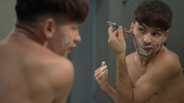 Young Man Shaving Goatee in Slow Motion in Bathroom at Home