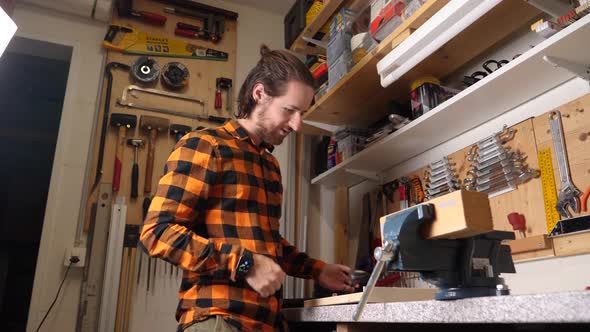 Young caucasian hipster with checkered shirt is wood crafting in his garage
