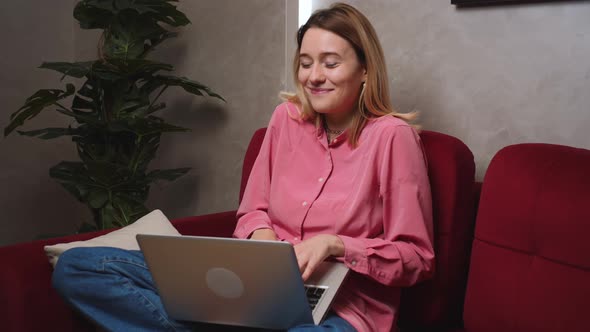 Happy Smiling Caucasian Woman Sitting on Couch at Home Use and Working on Laptop Computer