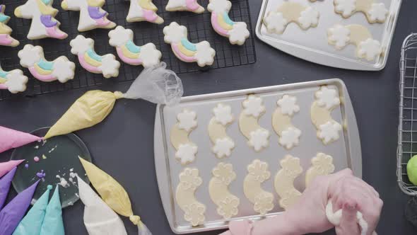 Step by step. Flat lay. Decorating unicorn theme sugar cookies with royal icing on baking sheet