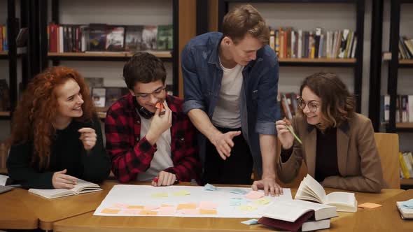 Group of Young Students of Four Explaining Course Work Study Together in Library
