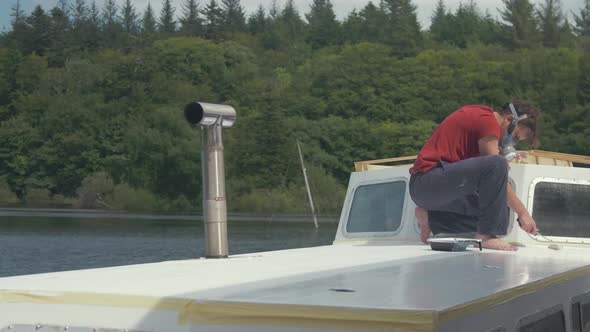 Timelapse young man painting white paint roof of wooden boat