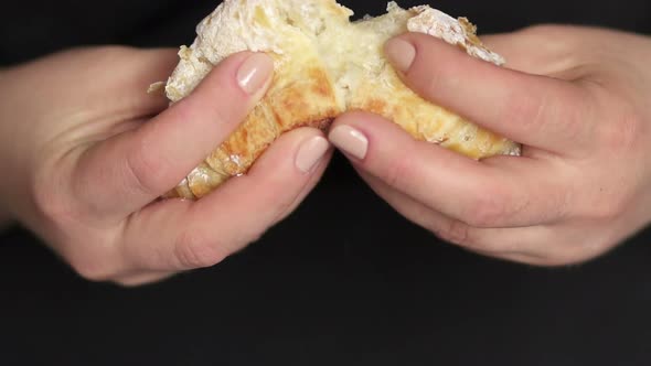 Closeup of Girl's Hands Breaks a Fresh Croissant