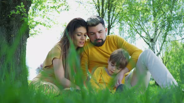 Young family reading a book outdoors