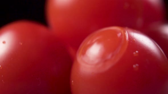 Macro shot. Clear water is poured onto a bunch of ripe red cherry tomatoes