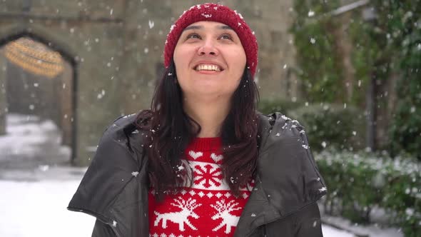 A Happy Young Woman Looks at the Snowfall