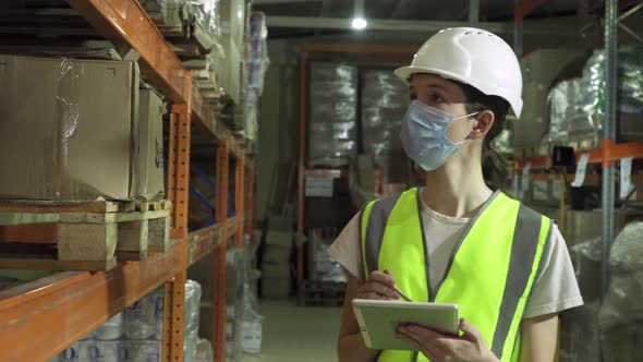 A Female Supervisor Wearing a Safety Vest Hard Hat and Face Mask During an Inspection at a Factory