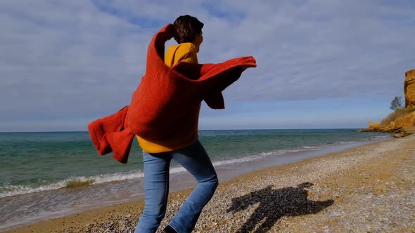 Hiker Woman Wearing Yellow Sweater Trekking in Cold Sunny Weather Hair Blowing in Wind