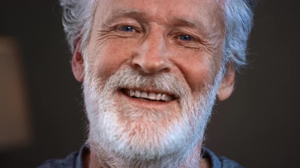 A Grayhaired Old Man with a Beard Laughs and Smiles for the Camera