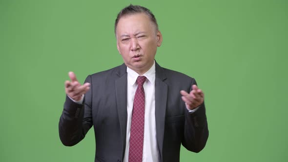 Mature Confused Japanese Businessman Shrugging Shoulders