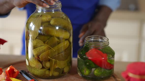 Front View Bottles with Organic Cucumber and Unrecognizable African American Man Closing Marinated