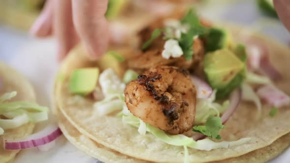 Fresh chipotle shrimp tacos with cotija cheese on a white corn tortillas.