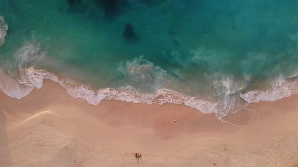 Aerial view at clear blue beach waves that slowly rolling in