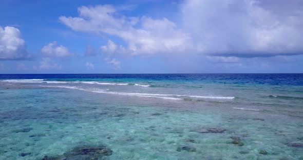 Luxury flying tourism shot of a sandy white paradise beach and blue water background in 4K