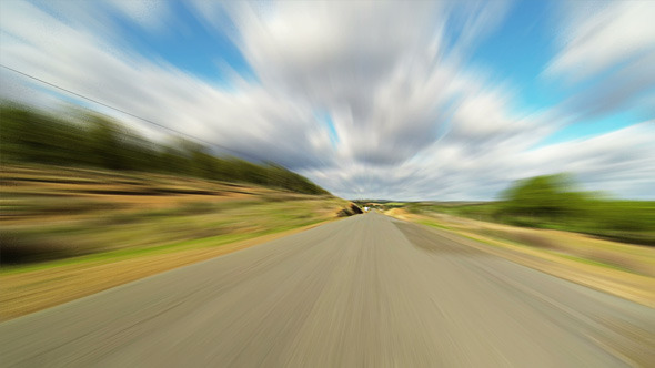 Fast Driving Car on the Road in Green Fields alt