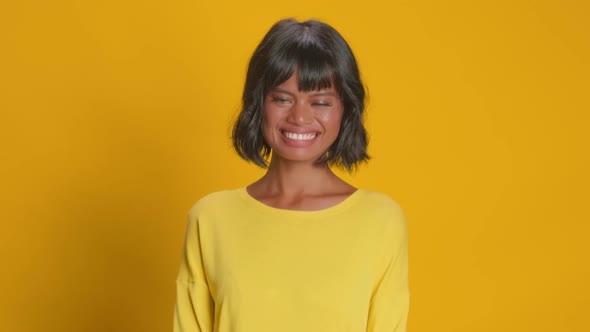 Positive Woman Smiles Broadly Has Upbeat Mood Over Yellow Background