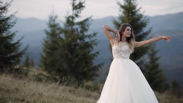 Beautiful Lovely Stylish Bride in White Wedding Dress Waiting for Groom on Mountain Slope Hill