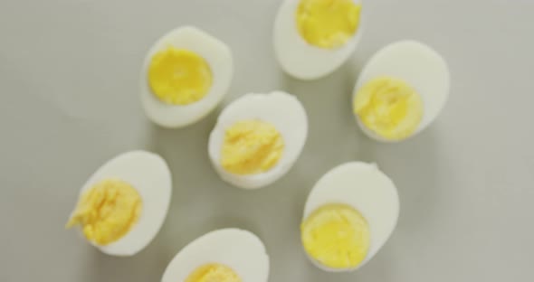Video of overhead view of halves of hard boiled eggs on grey background