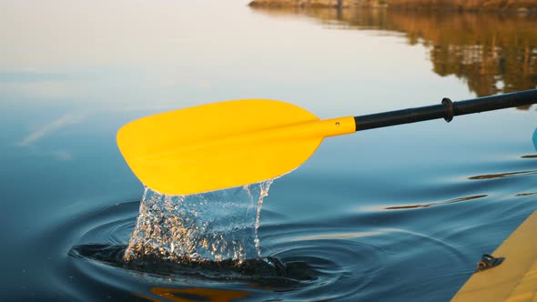 Yellow Oar Paddles in Blue Lake on Kayak at Sunset Close-up, Secluded Vacation