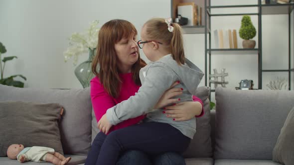 Caring Mom and Down Syndrome Child Bonding on Sofa