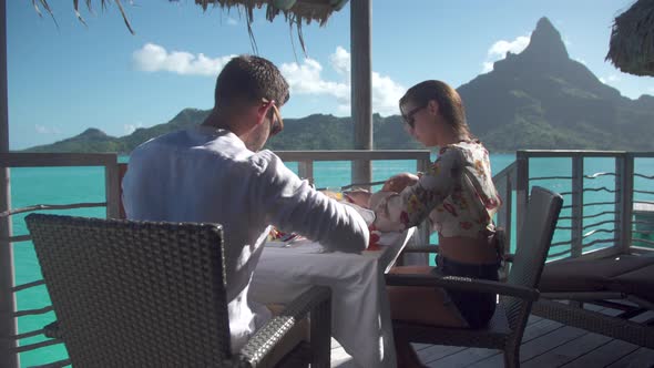 A man and woman couple eating breakfast outside at a tropical island resort