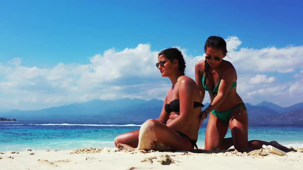 Pretty smiling girls relaxing in the sun at the beach on sunny blue and white sand background 4K