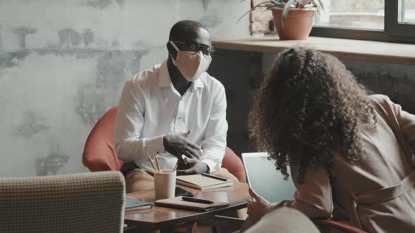 African-American Businessman in Face Mask Talking to Female Colleague