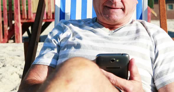 Senior man talking on mobile phone while relaxing on sunlounger