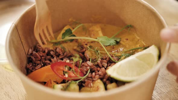 Woman Hand Takes Porridge Dish with Fork From Paper Bowl