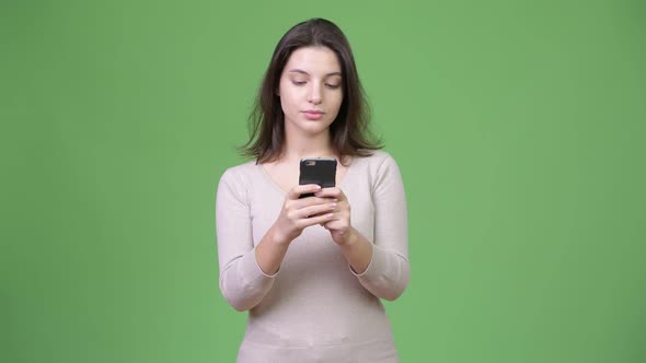 Young Beautiful Woman Using Phone Against Green Background