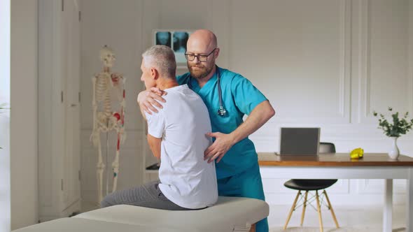 An Adult Man Trains Muscle Strength With a Professional Doctor in a Modern Rehabilitation Clinic
