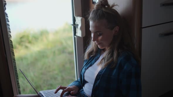 Woman Freelancer Working at a Laptop While Sitting in a Car Typing Text and Remote Work in Nature