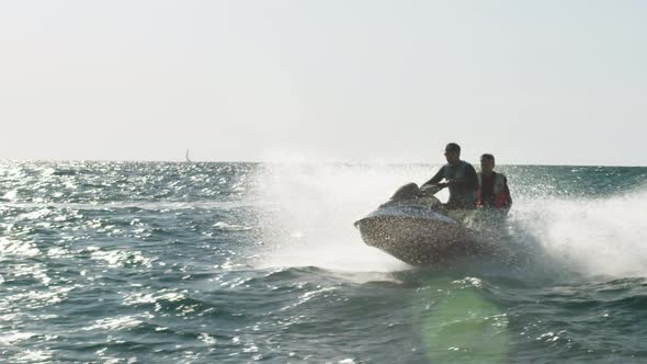 Two Persons in Life Jackets are Moving on Jet Ski in the Sun