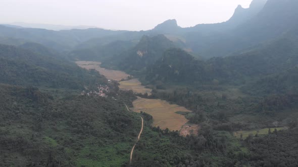 Aerial: flying over rice paddies unique valley scenic cliffs rock pinnacles tropical jungle stunning