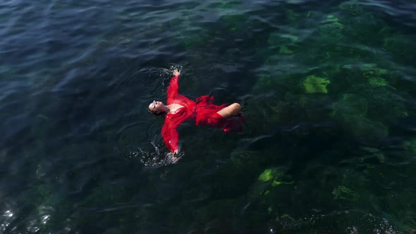 Woman in a Red Long Dress Is Lying on Her Back Bathing in the Green