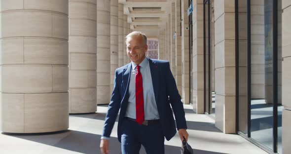 Happy Mature Businessman Walking Outside and Giving High Five to Colleagues