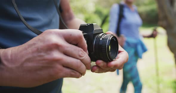 Mid section of senior man using digital camera to take pictures in the woods while hiking