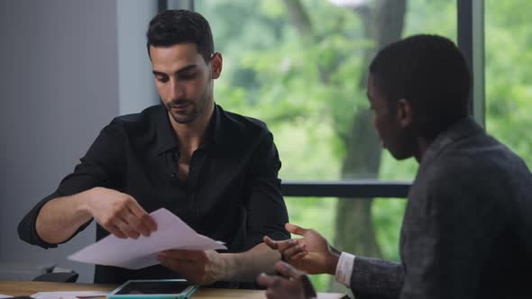 Middle Eastern CEO and African American Manager Shaking Hands Sitting in Office Analyzing Strategy