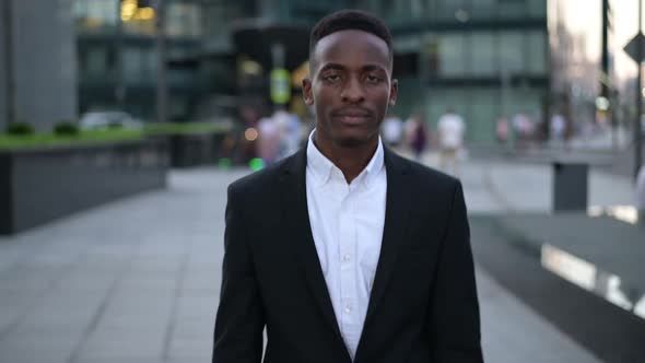 A young black guy goes straight to the camera in the evening through the city