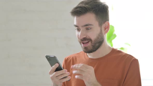 Young Man Celebrating Success on Smartphone