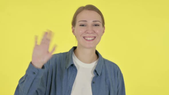 Young Woman Waving Welcoming on Yellow Background