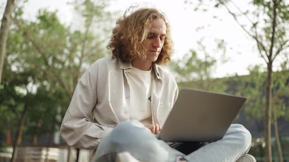 Positive curly-haired man working on laptop