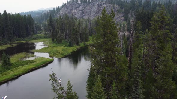 Clockwise drone shot revealing paddleboarders and kayakers on the Payette River from behind trees. T