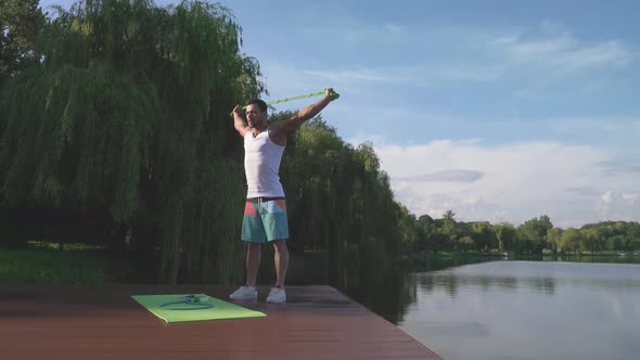 Young Bodybuilder in Sport Clothes Doing Squat Down Outdoors