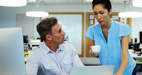 Business colleagues discussing over laptop