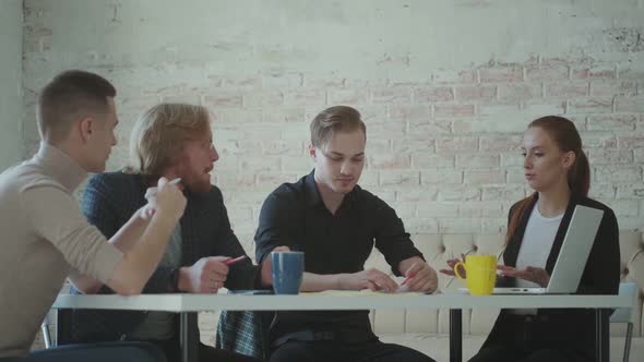 Team of Young Professionals Communicate at a Table in the Office