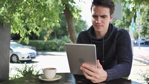 Young Man Upset By Loss While Working on Tablet Computer